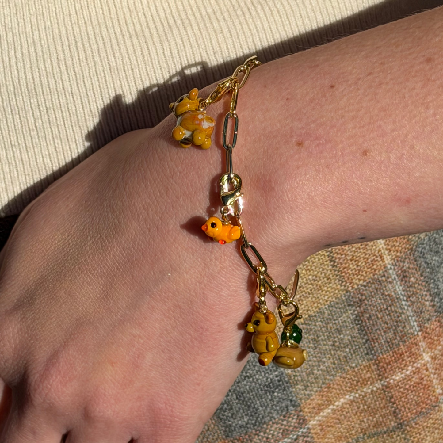 Bracelet with colorful charms on a wrist against a textured fabric background