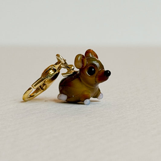 Glass mouse charm with gold clasp on a white background