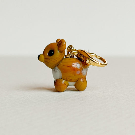 Glass deer charm with gold clasp on a white background