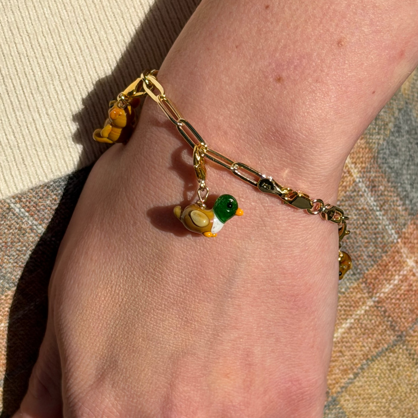 Bracelet with charms on a wrist against a textured fabric background