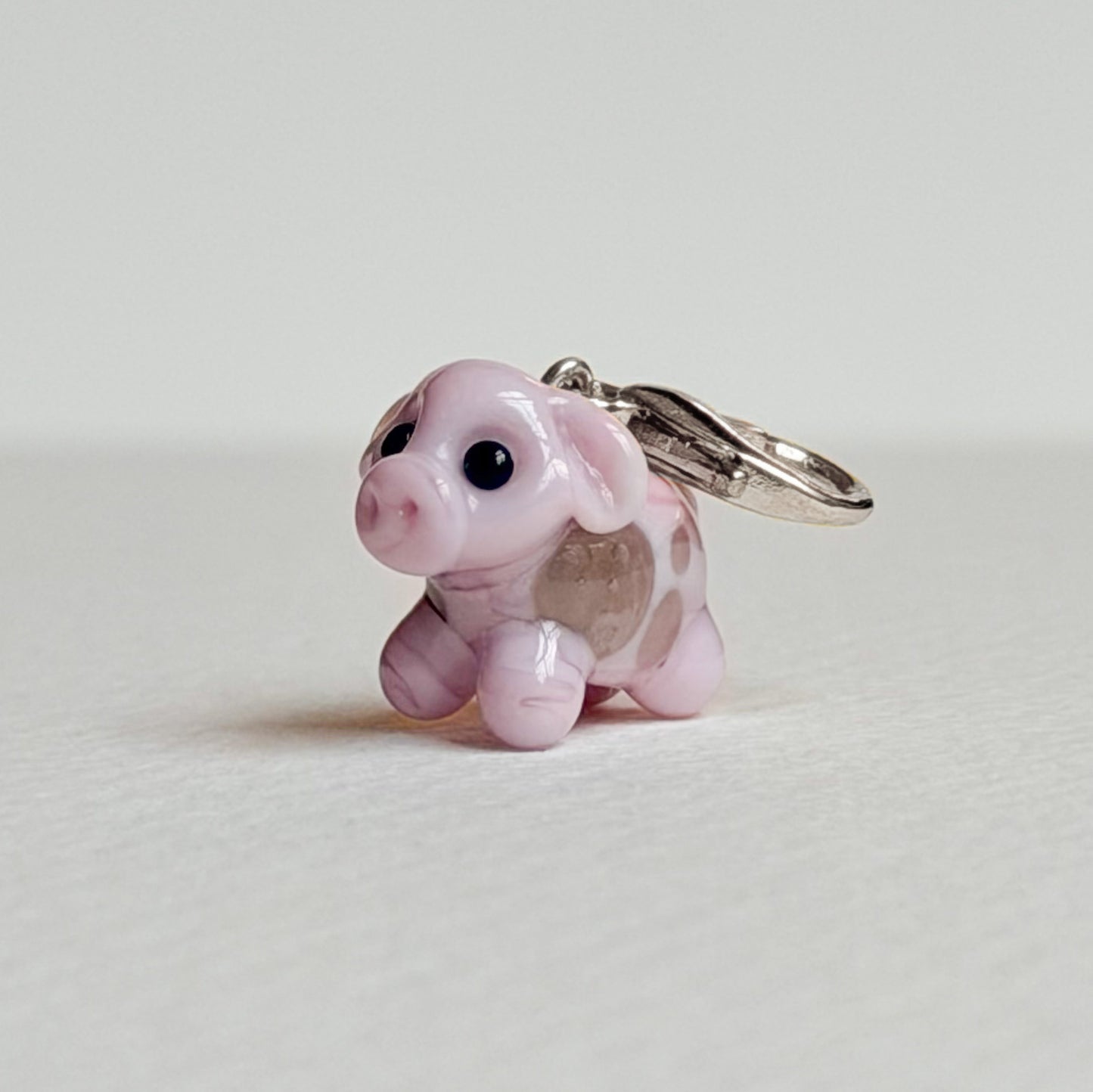 Pink cow charm with silver hardware on a white background