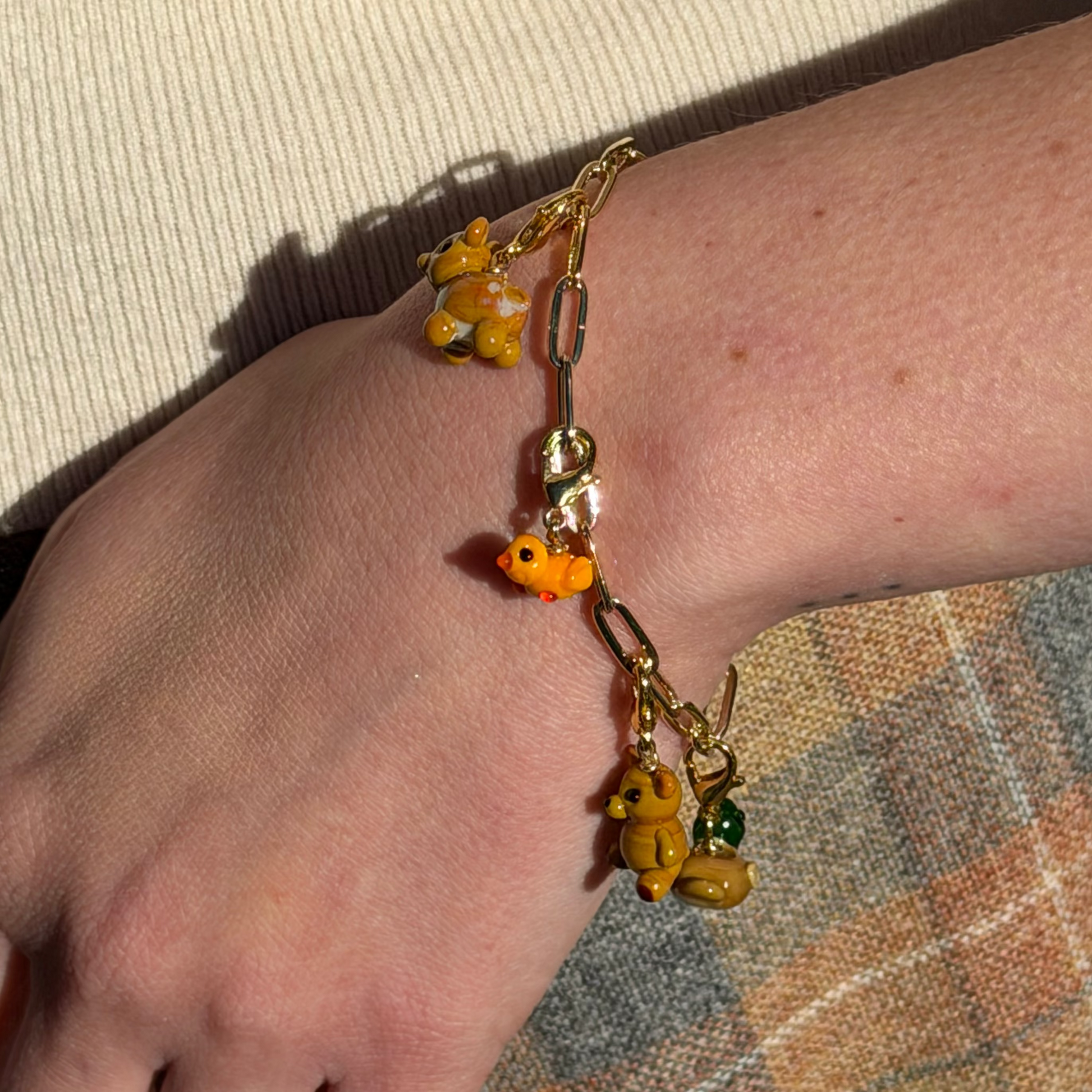 Bracelet with colorful charms on a wrist against a textured fabric background