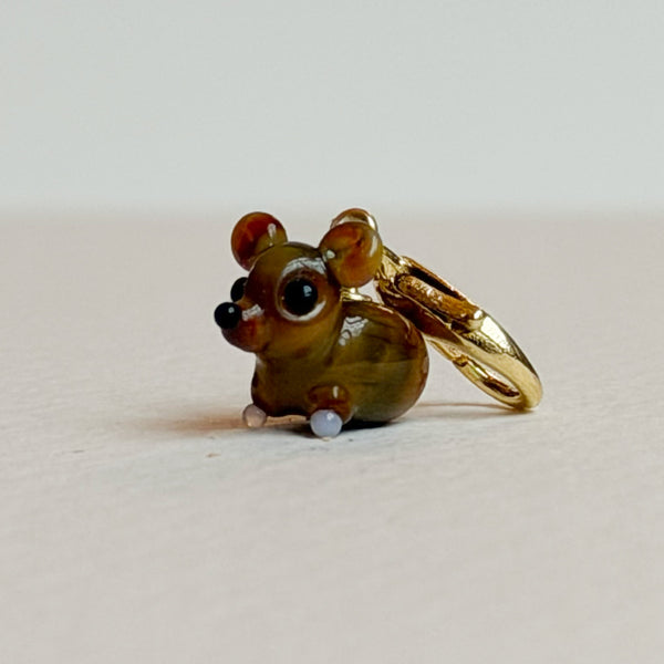 Glass mouse charm with gold clasp on a white background
