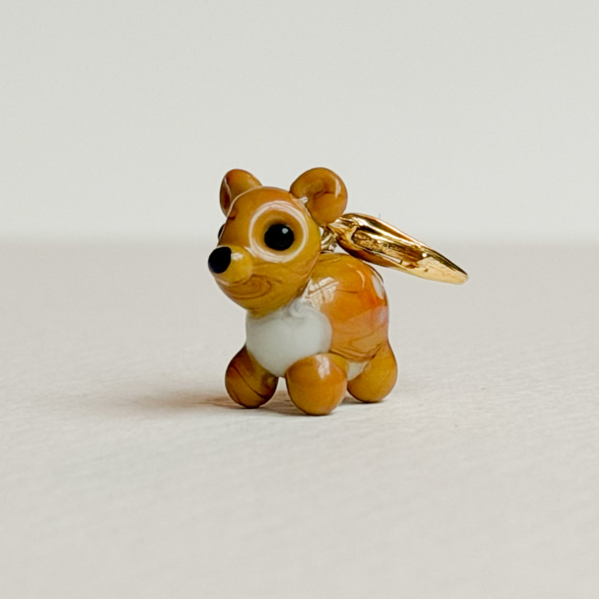 Glass deer charm with gold clasp on a white background