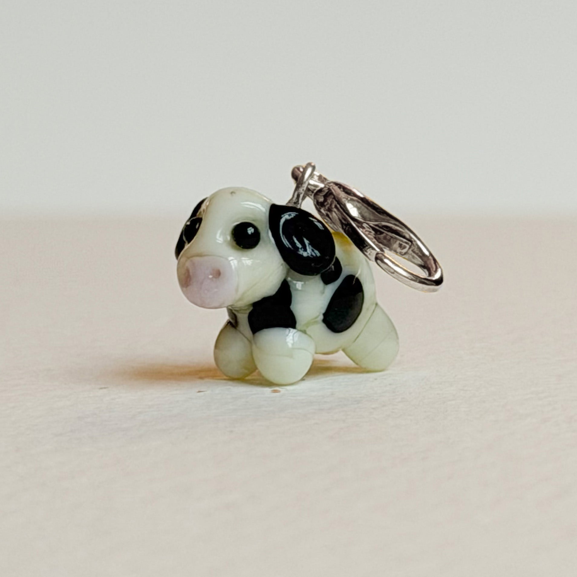 Small cow-shaped charm with black spots on a white background