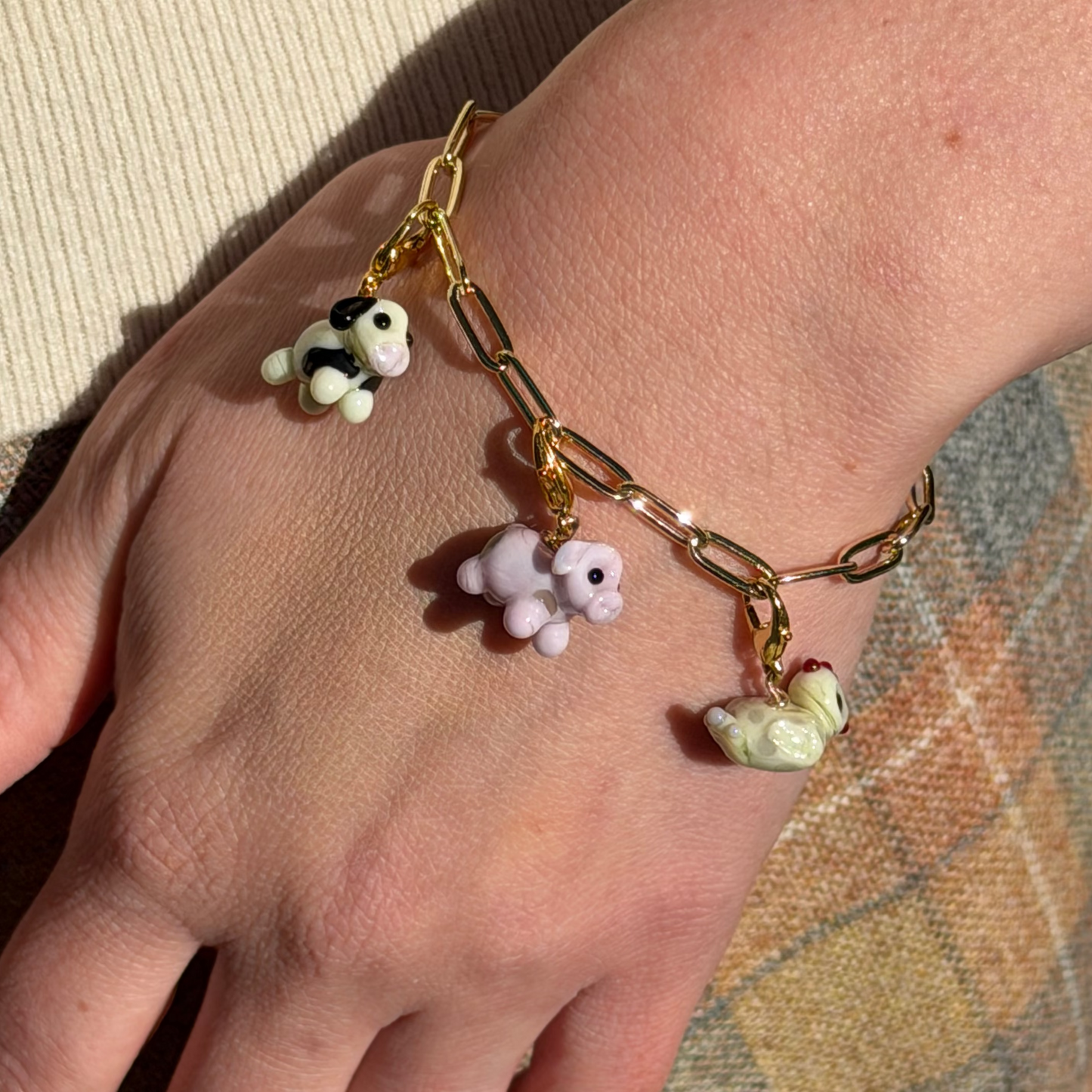 Bracelet with animal charms on a wrist against a neutral background