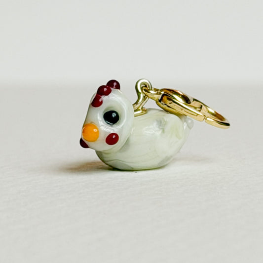 Small chicken-shaped charm with gold hardware on a light gray background