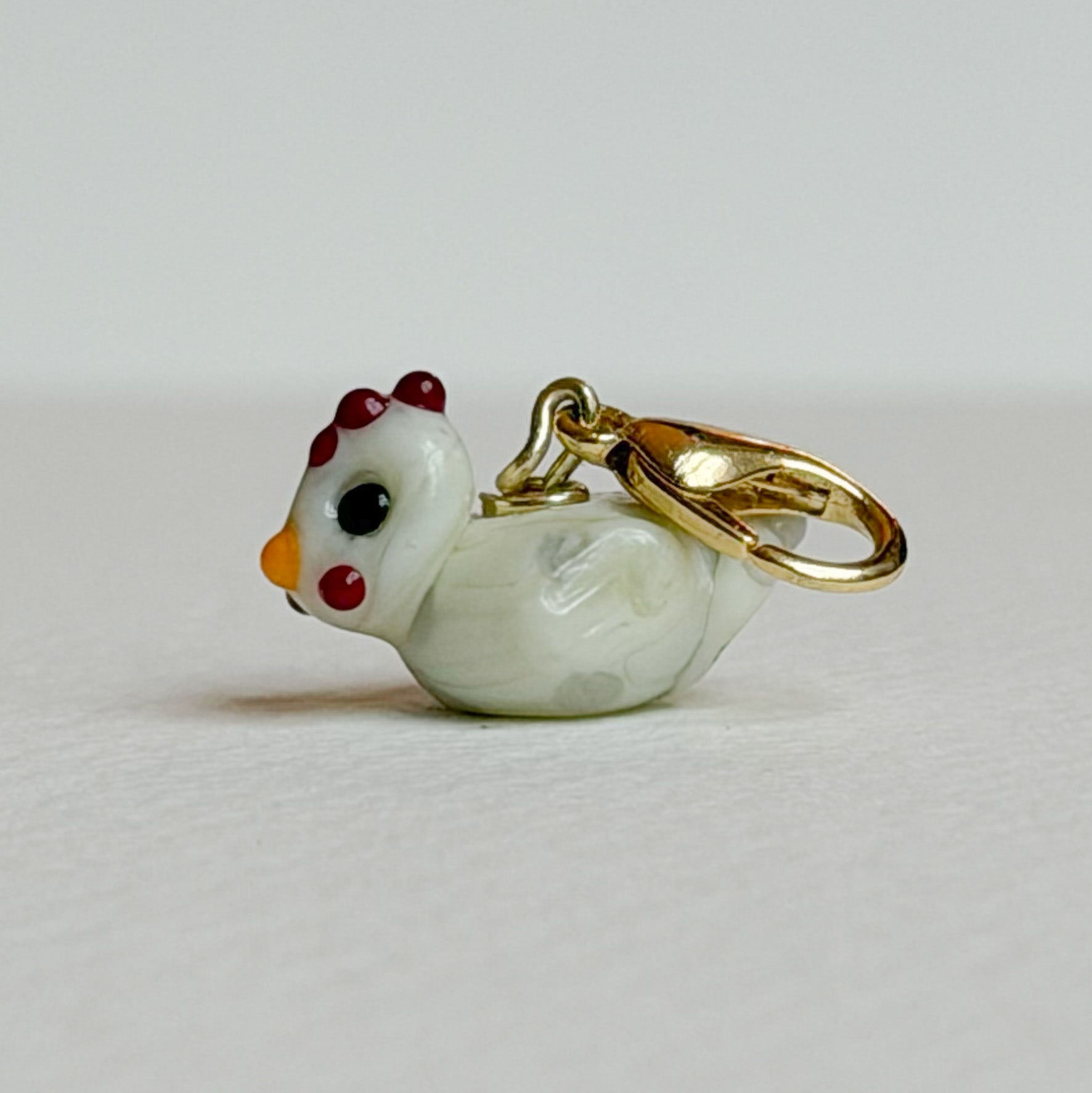 Chicken-shaped charm on a light gray background