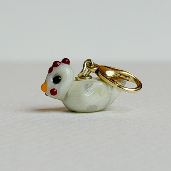 Chicken-shaped charm on a light gray background