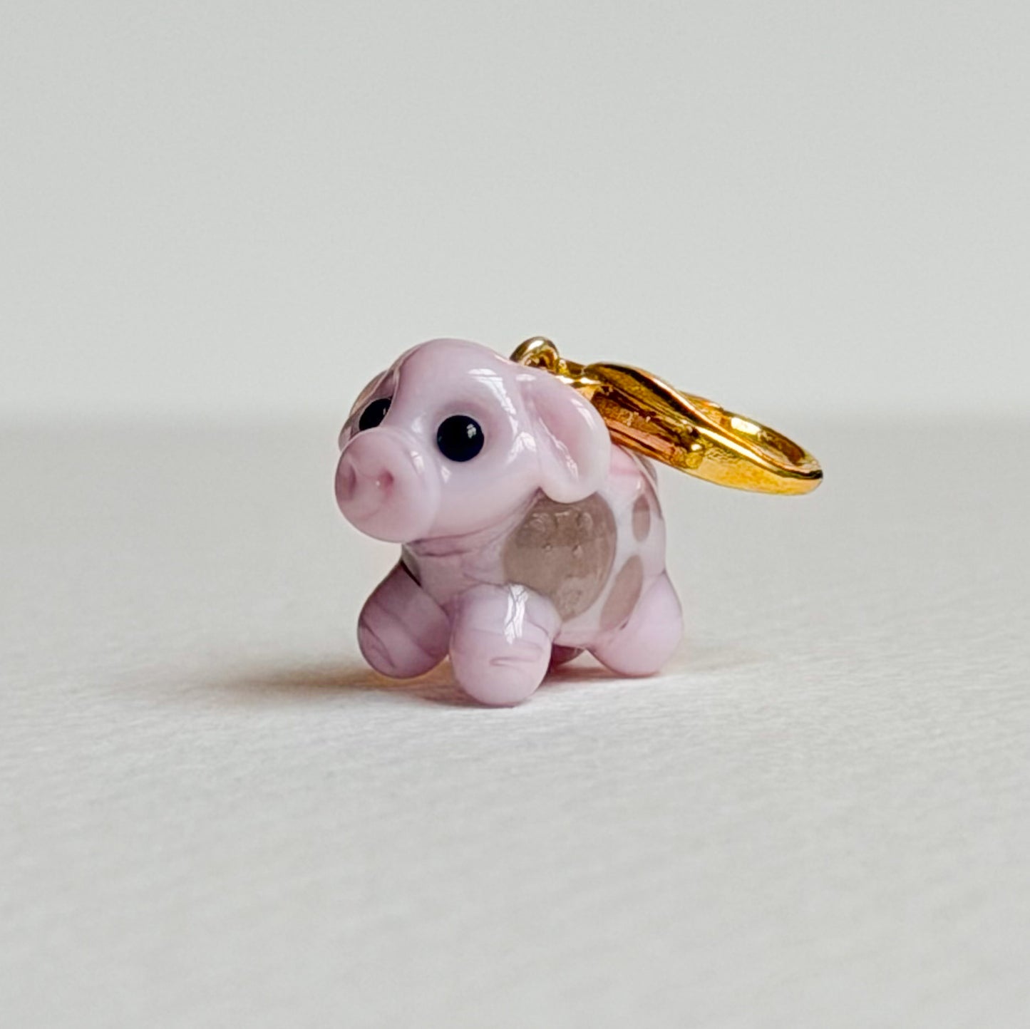 Pink cow charm with gold hardware on a white background