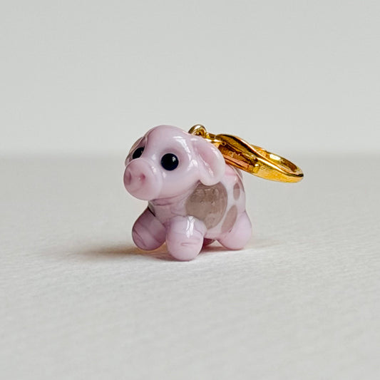 Pink cow charm with gold hardware on a white background