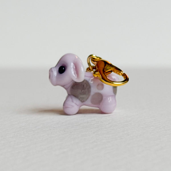 Pink cow charm with gold hardware on a white background