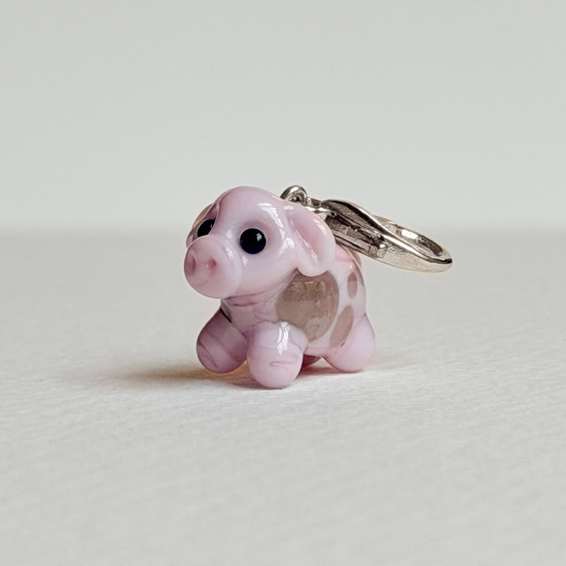 Pink cow charm with silver hardware on a white background