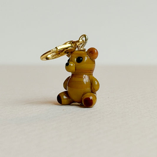 Small teddy bear charm with a gold clasp on a light gray background